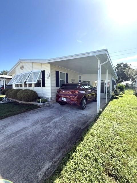 A maroon SUV is parked under the carport of a light-colored manufactured home — 1001 W STARKEY ROAD UNIT 475, LARGO, FL