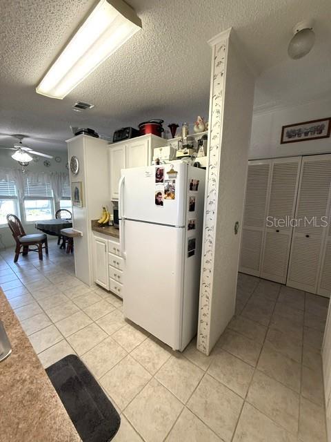 A kitchen features white cabinets, a white refrigerator, and light-colored tile flooring — 1001 W STARKEY ROAD UNIT 475, LARGO, FL