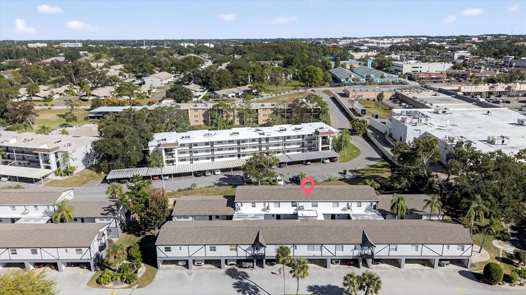 An aerial view shows multi-story apartment buildings with covered parking and surrounding landscaping — 1146 KING ARTHUR COURT UNIT 110, DUNEDIN, FL