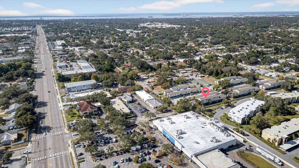 An aerial view shows a commercial area with a large store and surrounding residential buildings — 1146 KING ARTHUR COURT UNIT 110, DUNEDIN, FL