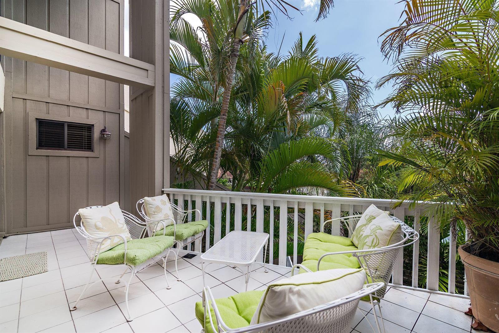 A balcony with white metal furniture, green cushions, and palm trees in the background — 1605 S Us Highway 1 # 8g, Jupiter FL 33477, JUPITER, FL