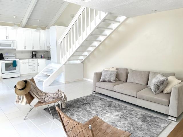 A bright living room features a white staircase, a gray sofa, and a modern kitchen — 1605 S Us Highway 1 # 8g, Jupiter FL 33477, JUPITER, FL