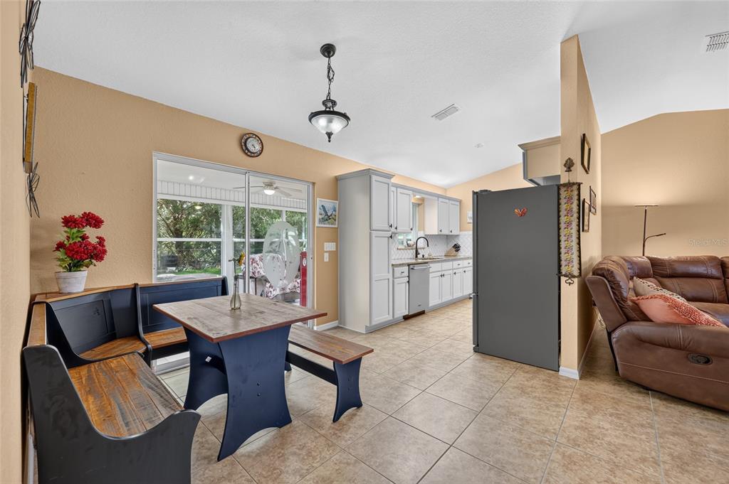 A kitchen and dining area with a breakfast nook, light cabinets, and tile flooring — 11946 SW 137TH LOOP, DUNNELLON, FL