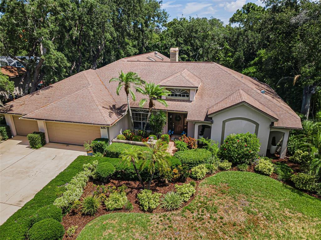 An aerial view shows a single-story house with a brown shingled roof and landscaped yard — 1680 SPARKLING COURT, DUNEDIN, FL