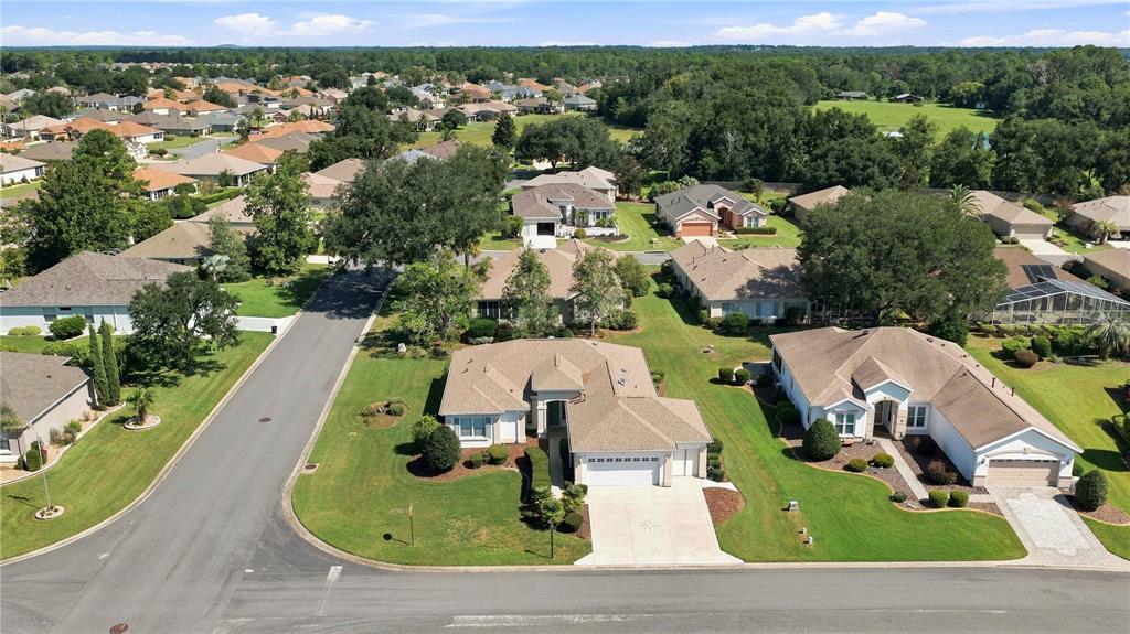 An aerial view shows suburban houses with tan roofs and green lawns along a paved street — 9317 124TH PLACE, SUMMERFIELD, FL