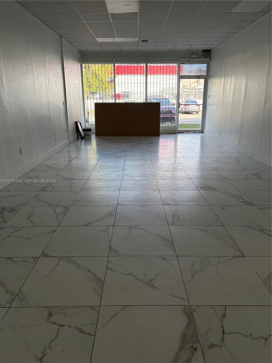 An empty commercial space features white marble-patterned tile floors and a large front window — 10240 SW 56th St # 105, Miami FL 33165, MIAMI, FL