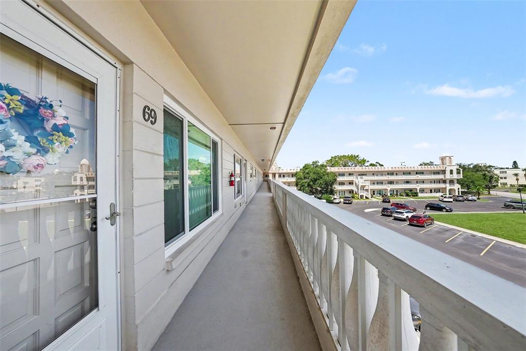 An exterior walkway with a white railing overlooks a parking lot and apartment buildings — 2284 PHILIPPINE DRIVE UNIT 69, CLEARWATER, FL
