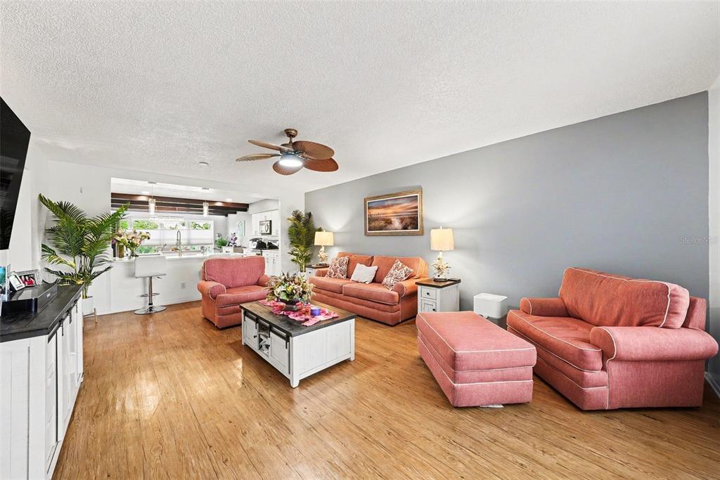 A living room features wood-look flooring, coral-colored seating, and an open view to the kitchen — 2284 PHILIPPINE DRIVE UNIT 69, CLEARWATER, FL