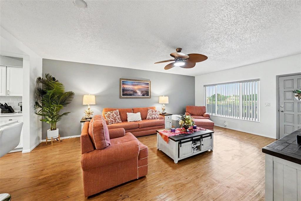 A living room features orange sofas, a white coffee table, and a ceiling fan — 2284 PHILIPPINE DRIVE UNIT 69, CLEARWATER, FL