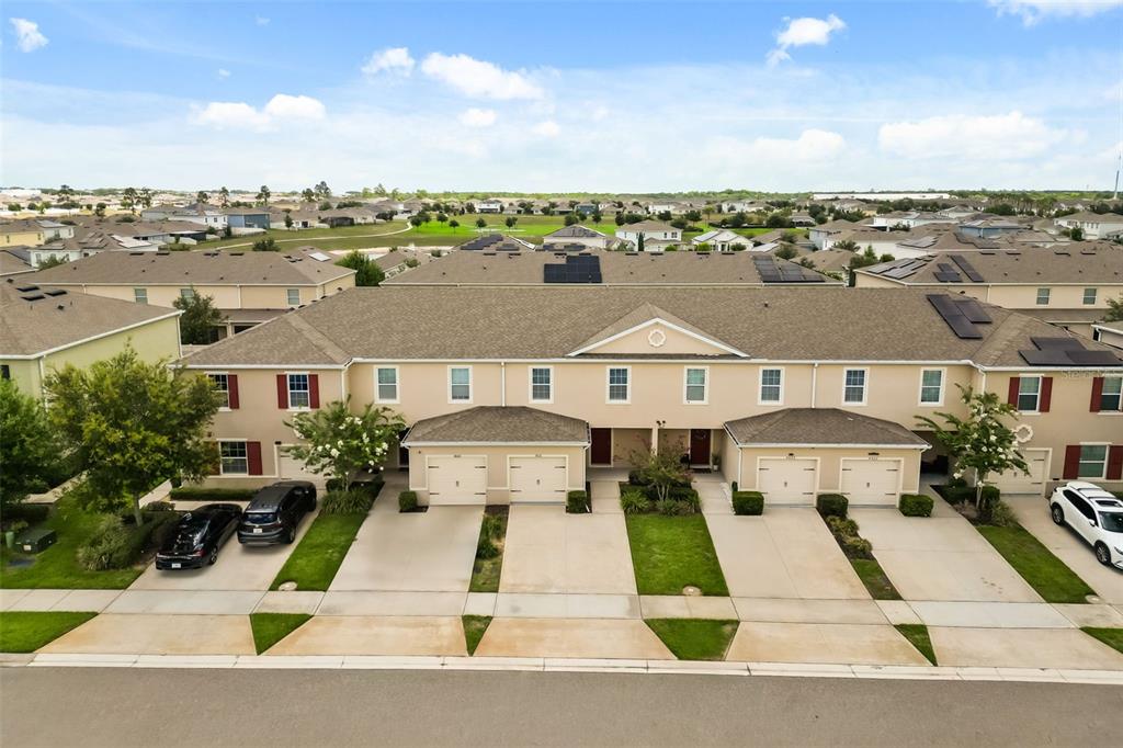 An aerial view of a tan townhouse complex with attached garages and a shared driveway — 9031 WILDFLOWER LANE, KISSIMMEE, FL