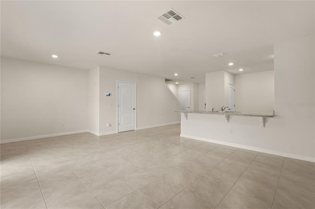 An open-concept living area features light-colored tile flooring, a breakfast bar, and recessed lighting — 9031 WILDFLOWER LANE, KISSIMMEE, FL