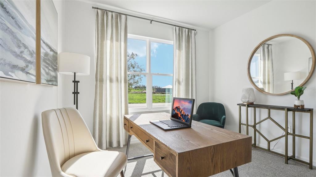 A home office features a wooden desk, a cream chair, and a large round mirror — 13609 NEW JADE AVENUE, WIMAUMA, FL