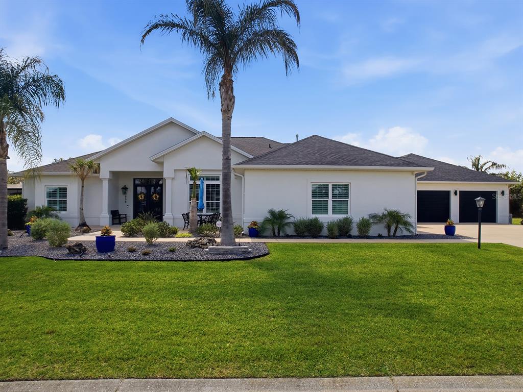 A single-story house with white stucco walls, a dark roof, and a palm tree — 858 PINCKNEY LANE, THE VILLAGES, FL