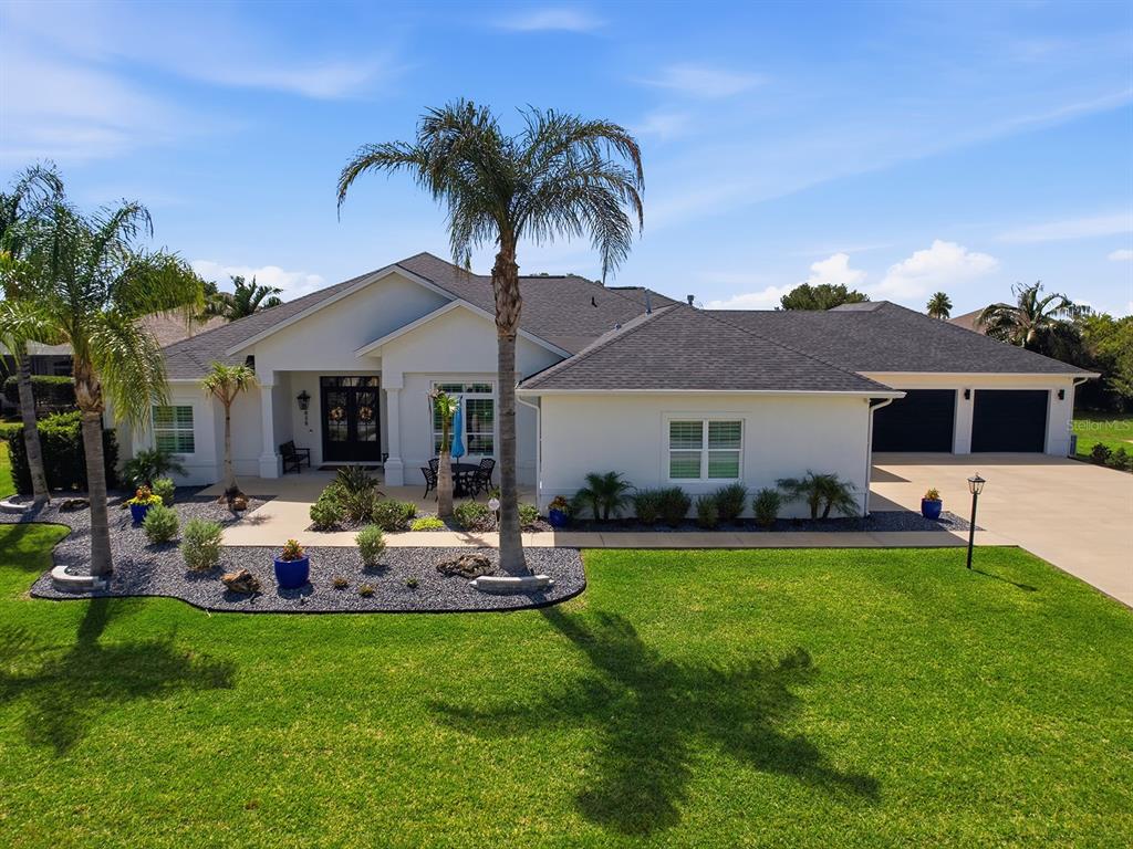A single-story house with a white exterior, dark roof, and a palm-lined front yard — 858 PINCKNEY LANE, THE VILLAGES, FL