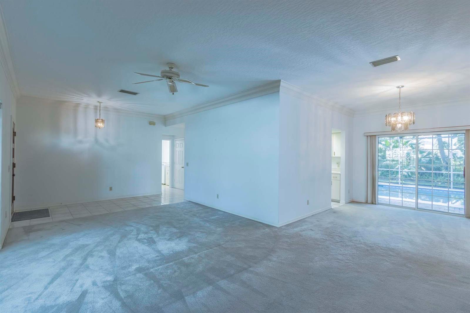 An interior view of a living area with gray carpeting, white walls, and sliding doors — 1027 Mangrove Lane, Vero Beach FL 32963, VERO BEACH, FL