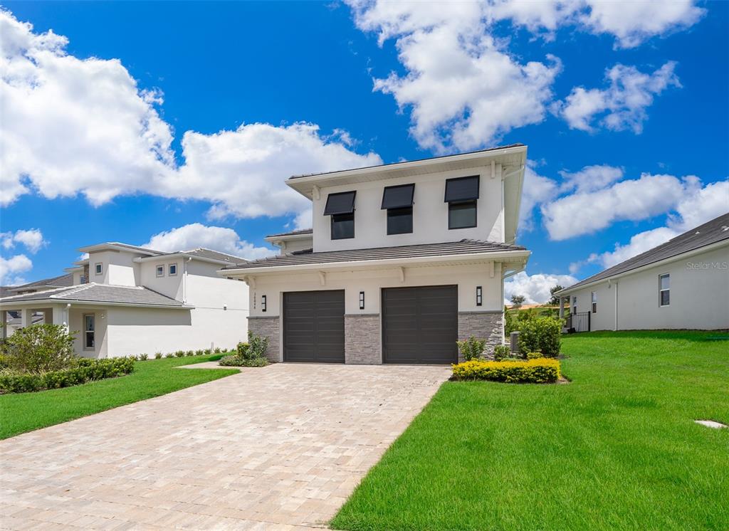 A modern open-concept living room and kitchen with high ceilings, tile floors, and large windows — 16046 VOLTERRA POINT, BELLA COLLINA, FL