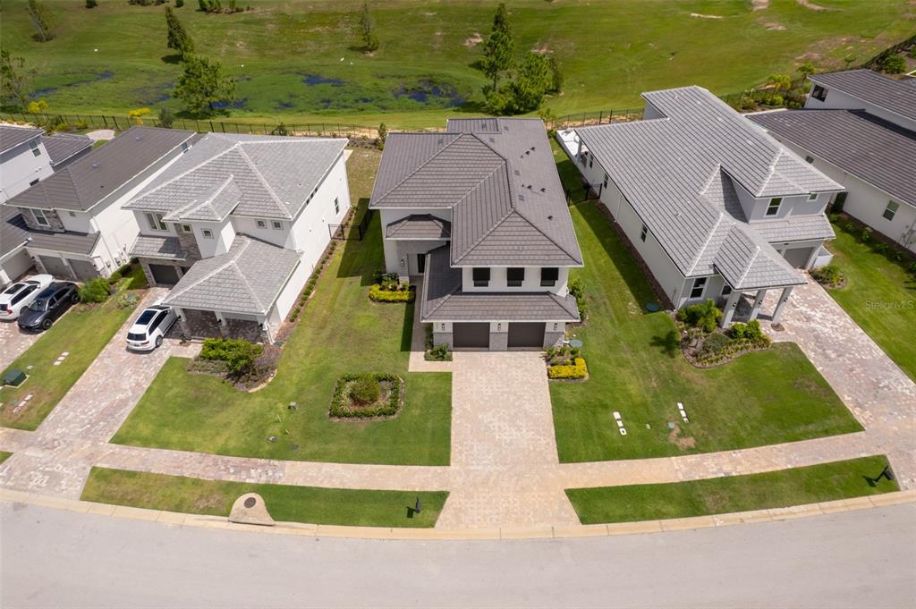 A living room with high ceilings, a white sectional sofa, and large windows overlooking a golf course — 16046 VOLTERRA POINT, BELLA COLLINA, FL