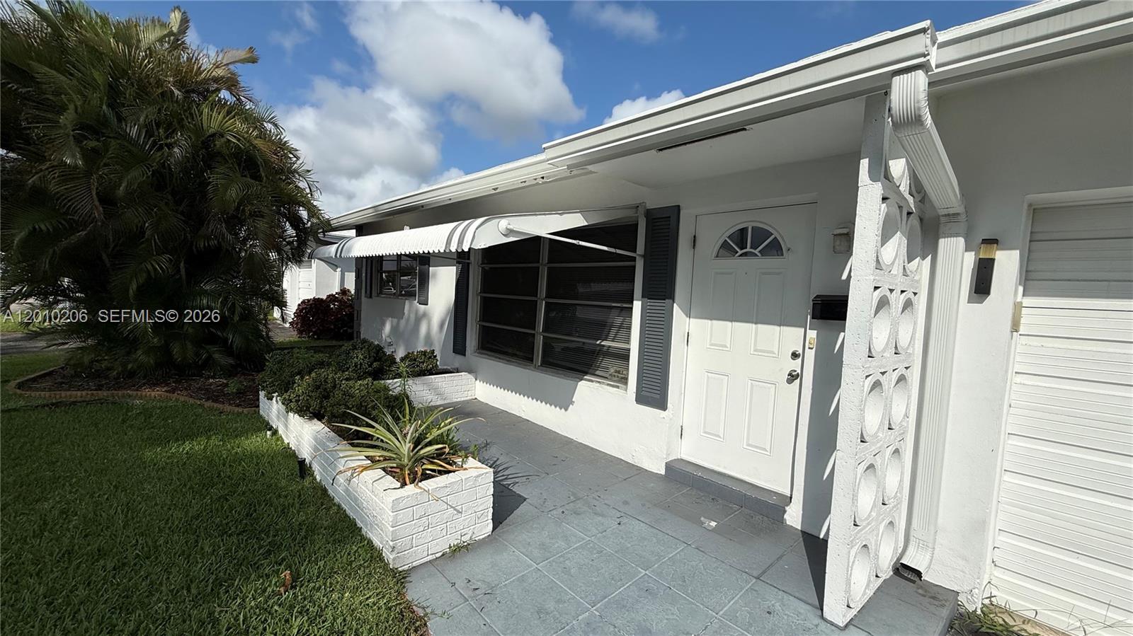 The exterior of a white house features a tiled porch, metal awning, and decorative screen — 3021 NW 2nd Ave, Pompano Beach FL 33064, POMPANO BEACH, FL