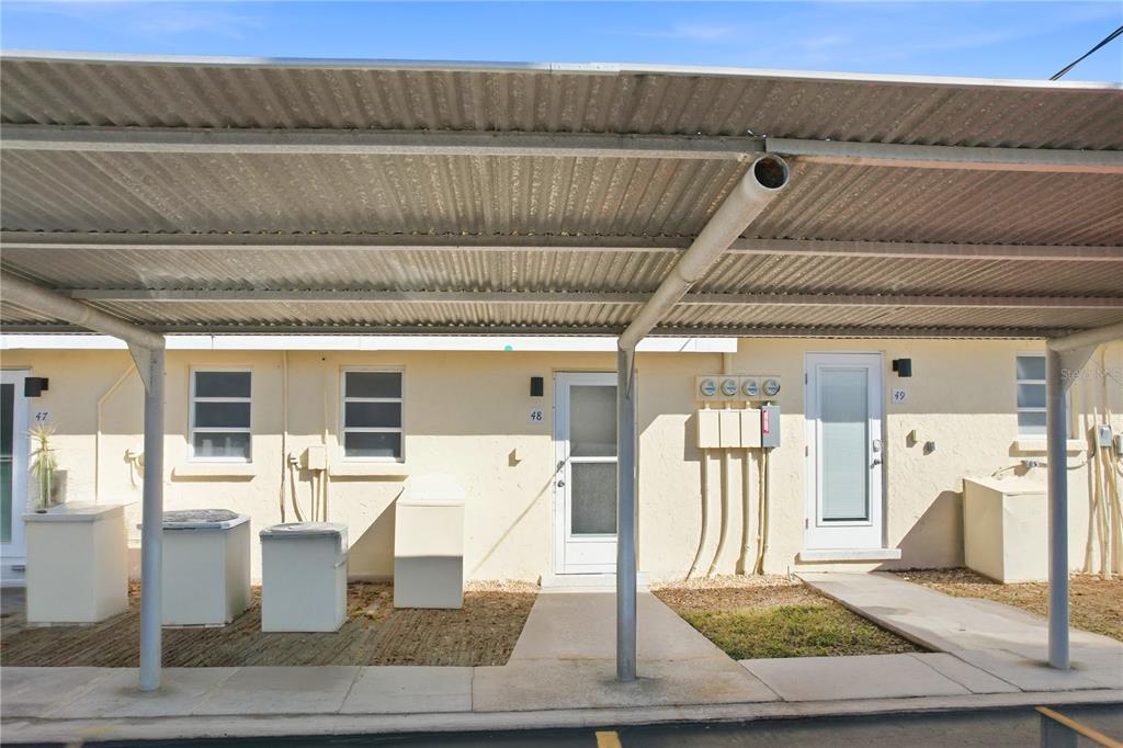 A covered parking area sits in front of two building units with numbered doors — 6006 MIDNIGHT PASS ROAD UNIT 48, SARASOTA, FL