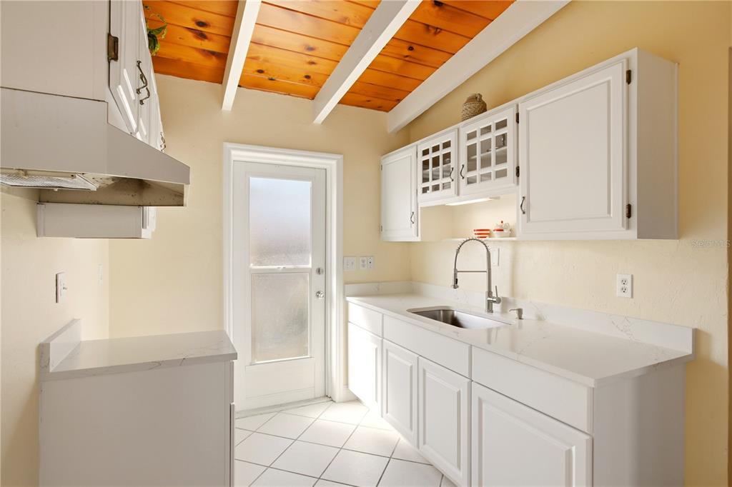 A kitchen features white cabinets, quartz countertops, a stainless steel sink, and a wood-paneled ceiling — 6006 MIDNIGHT PASS ROAD UNIT 48, SARASOTA, FL