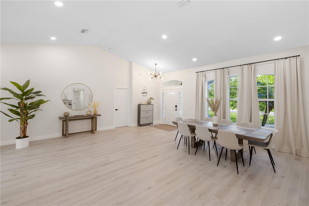 An entryway features light wood flooring, a modern sputnik chandelier, and a white front door — 5160 HORNBUCKLE BOULEVARD, NORTH PORT, FL