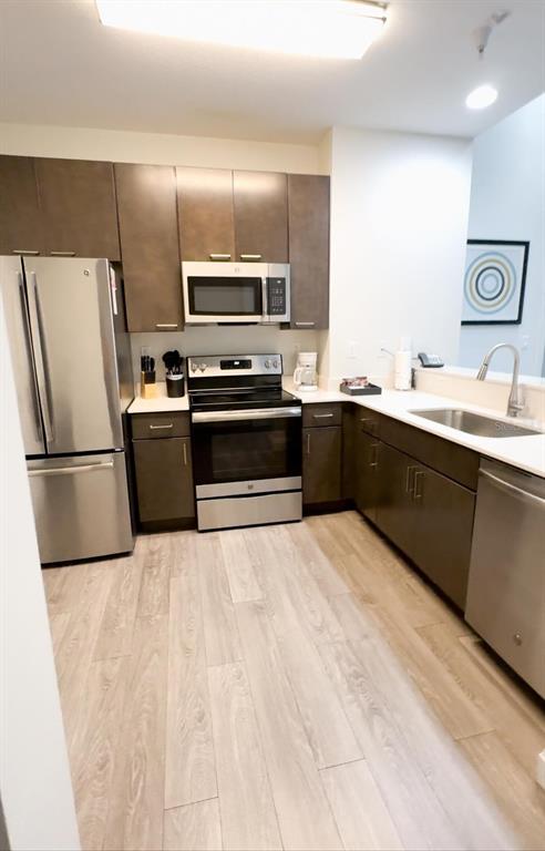 A modern kitchen features stainless steel appliances, dark wood cabinets, and light wood-look flooring — 14501 GROVE RESORT AVENUE UNIT 3128, WINTER GARDEN, FL