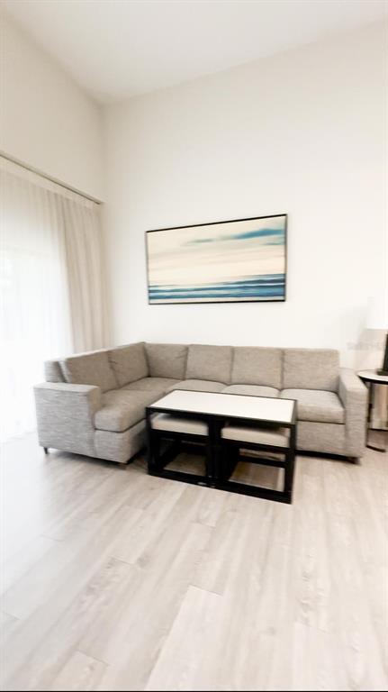 A living room features a grey sectional sofa, a coffee table, and abstract wall art — 14501 GROVE RESORT AVENUE UNIT 3128, WINTER GARDEN, FL