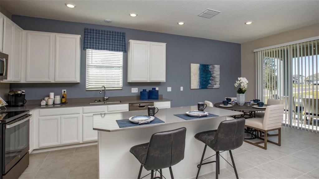 A kitchen features white cabinets, a gray island with bar stools, and a dining area — 643 GROVE STREET, WINTER HAVEN, FL