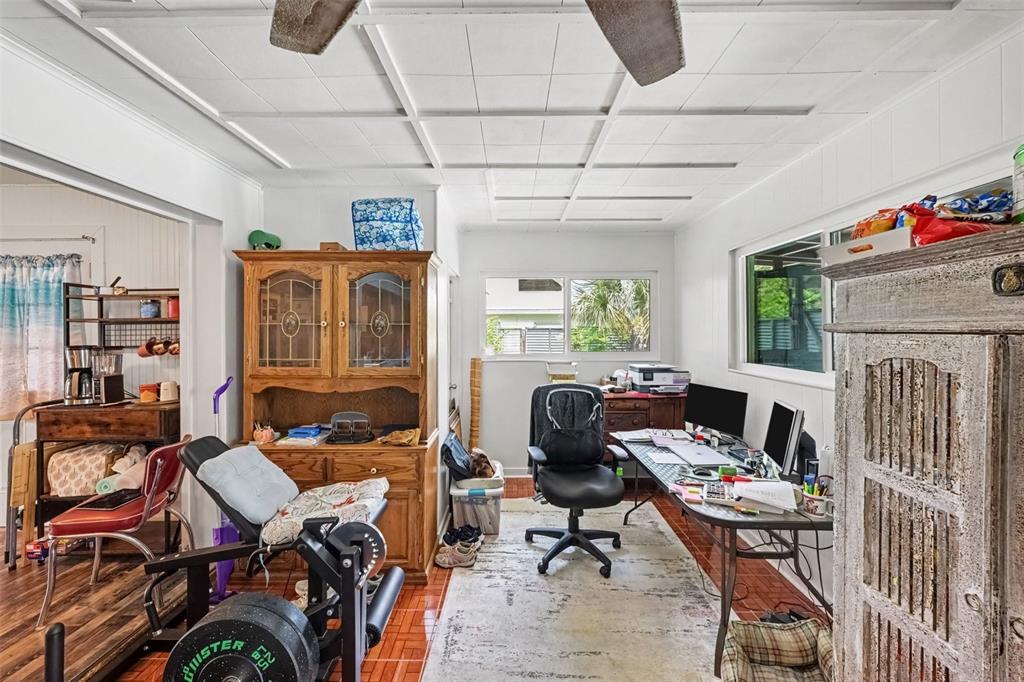 A home office features a desk, exercise equipment, a wooden hutch, and a tiled floor — 2731 PINE RIDGE DRIVE, TITUSVILLE, FL