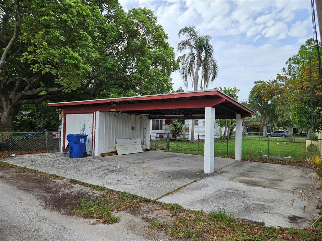 A detached carport with a red frame and white storage area sits on a concrete pad — 4605 8TH AVENUE N, ST PETERSBURG, FL