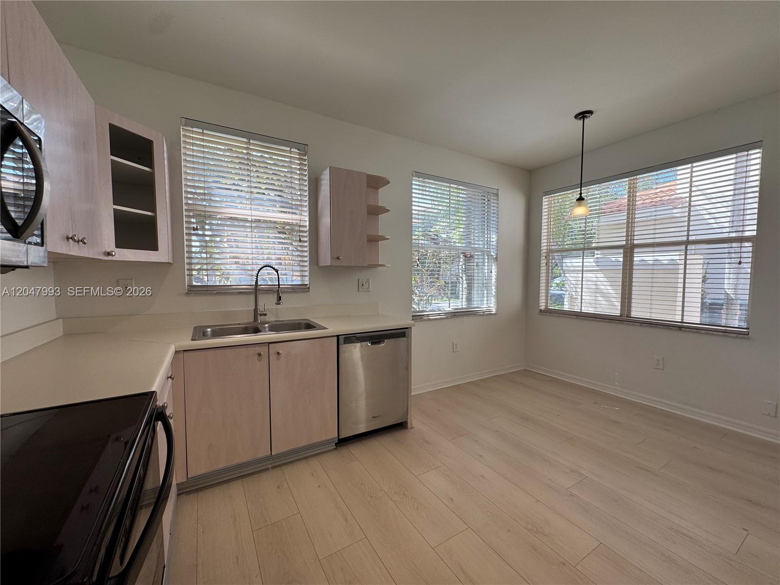 A kitchen features light wood cabinets, stainless steel appliances, and a dining area with windows — 1595 Seagrape Way, Hollywood FL 33019, HOLLYWOOD, FL