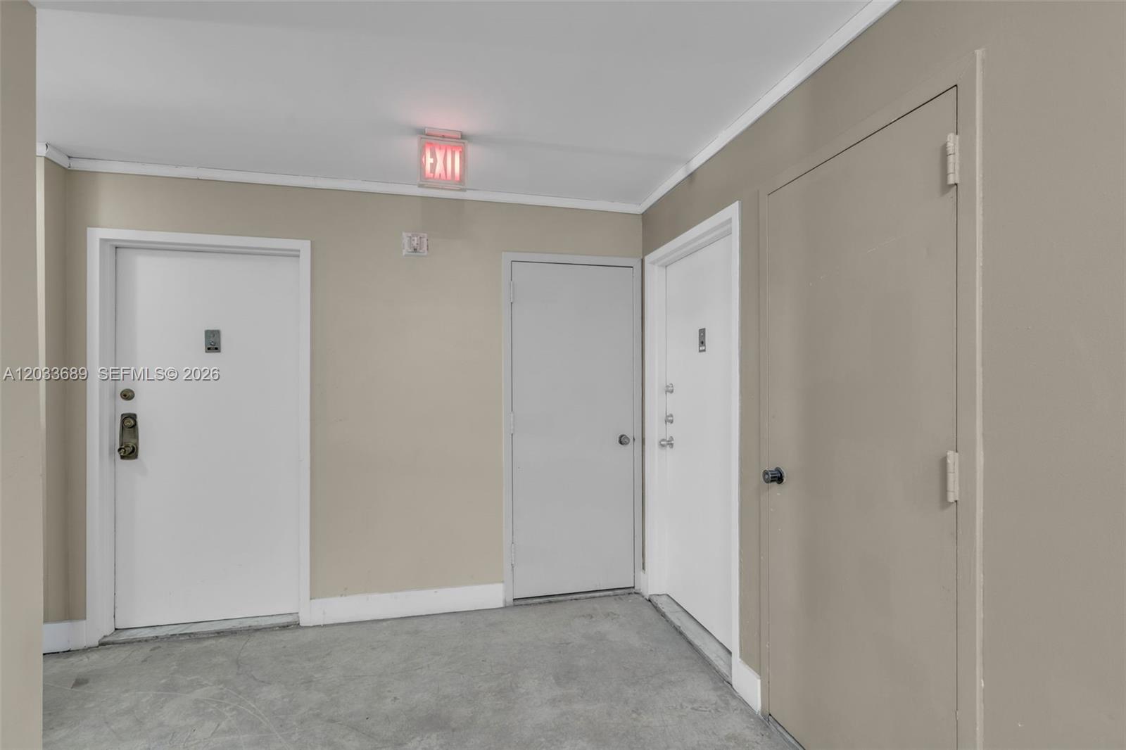 This interior hallway features beige walls, a concrete floor, and four closed doors — 1800 Collins Ave # 10F, Miami Beach FL 33139, MIAMI BEACH, FL