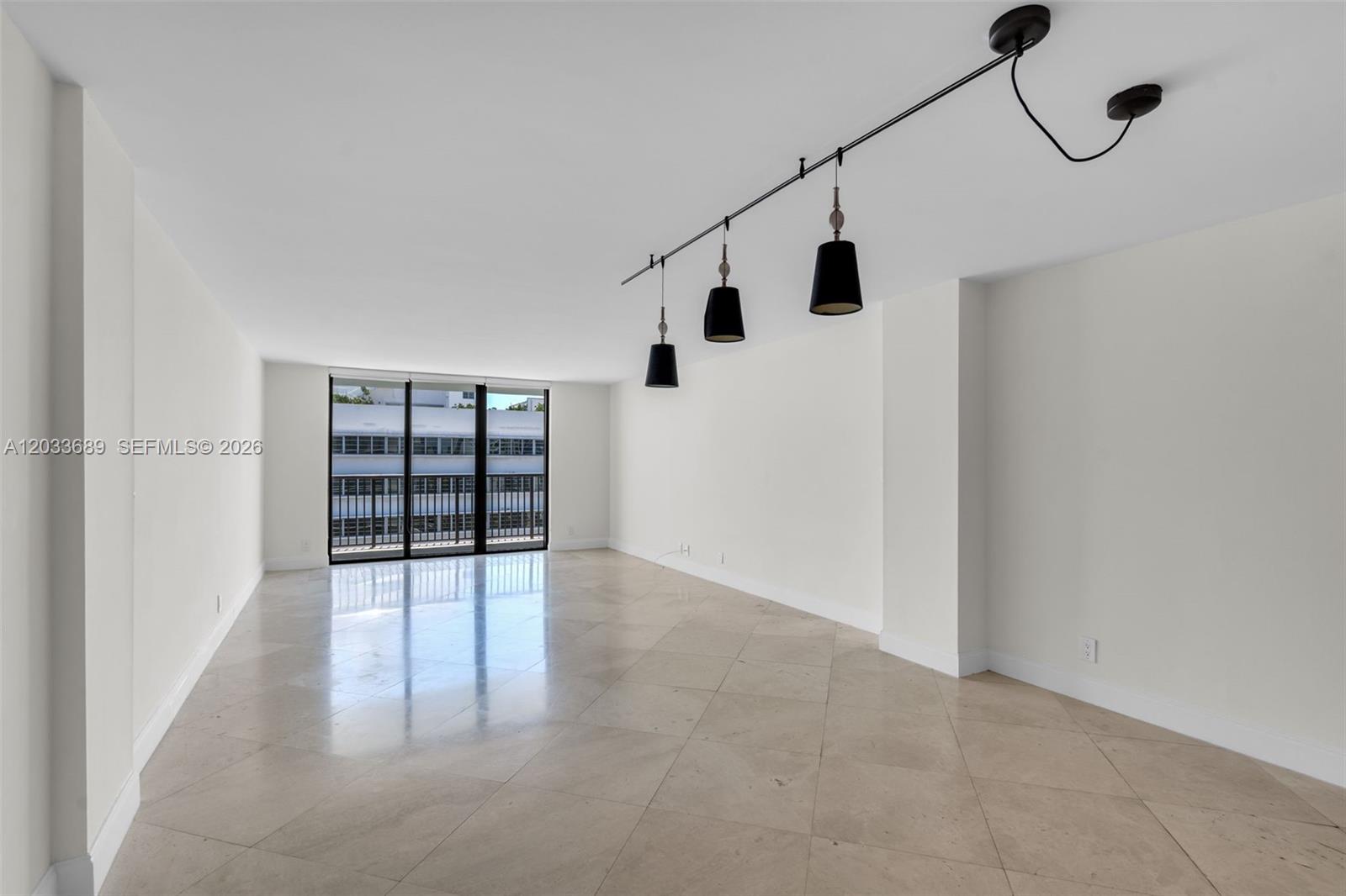 An empty room features white walls, tile flooring, and a three-light track fixture — 1800 Collins Ave # 10F, Miami Beach FL 33139, MIAMI BEACH, FL