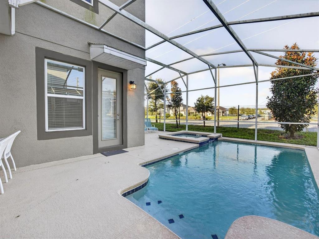 A swimming pool and spa are enclosed within a screened lanai next to a house — 620 STICKS STREET, DAVENPORT, FL