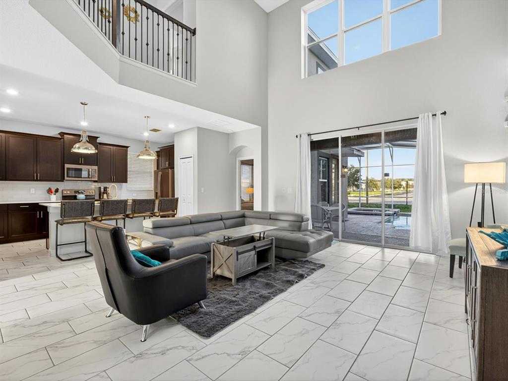 A living room with high ceilings, tile floors, and an open kitchen with dark cabinets — 620 STICKS STREET, DAVENPORT, FL
