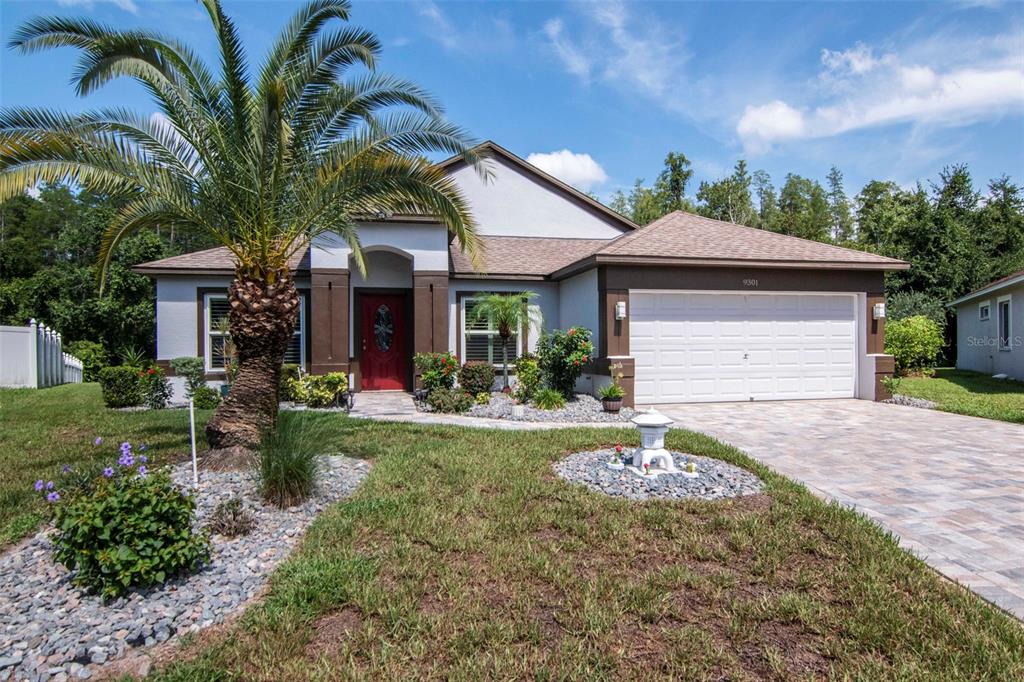 A single-story house with a palm tree, red front door, and two-car garage — 9301 BROOKHURST COURT, TAMPA, FL