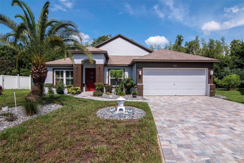 A single-story house with a white garage, red front door, and a palm tree — 9301 BROOKHURST COURT, TAMPA, FL