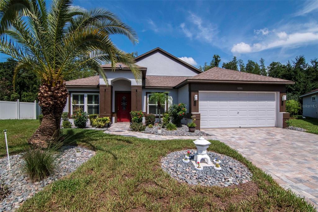 A single-story house with a white garage, a red front door, and a palm tree — 9301 BROOKHURST COURT, TAMPA, FL