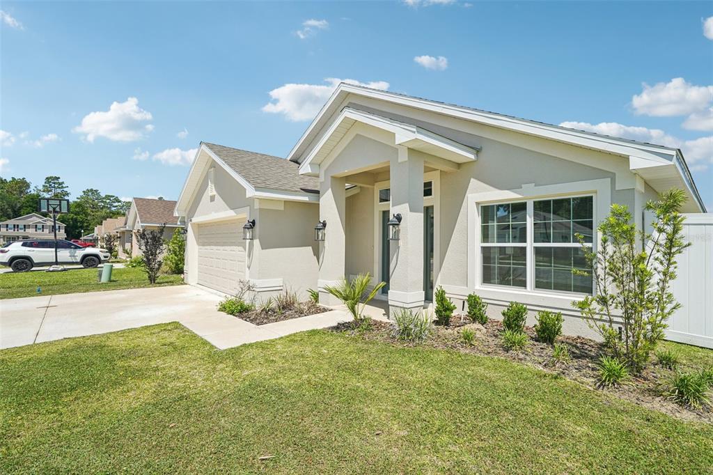 A single-story suburban house with a beige stucco exterior, a garage, and a front lawn — 4588 SE 25TH LOOP, OCALA, FL