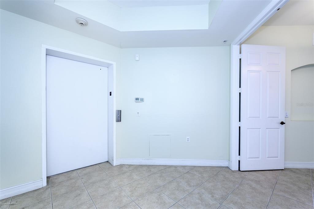 A room with light-colored walls, tile flooring, a white door, and a recessed ceiling area — 89 VIVANTE BOULEVARD UNIT 402, PUNTA GORDA, FL