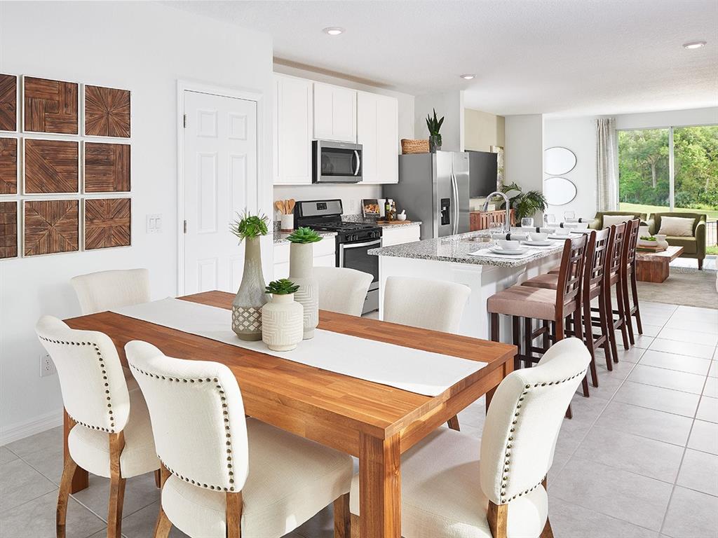 A dining area with a wooden table and upholstered chairs sits before an open kitchen — 5 DILLY COURT, PALM COAST, FL