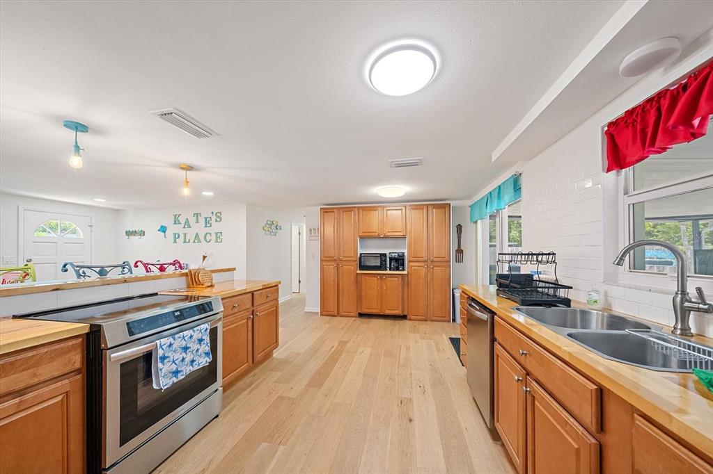 A kitchen features wooden cabinets, stainless steel appliances, light wood flooring, and a sink — 2923 LINWOOD DRIVE, SARASOTA, FL