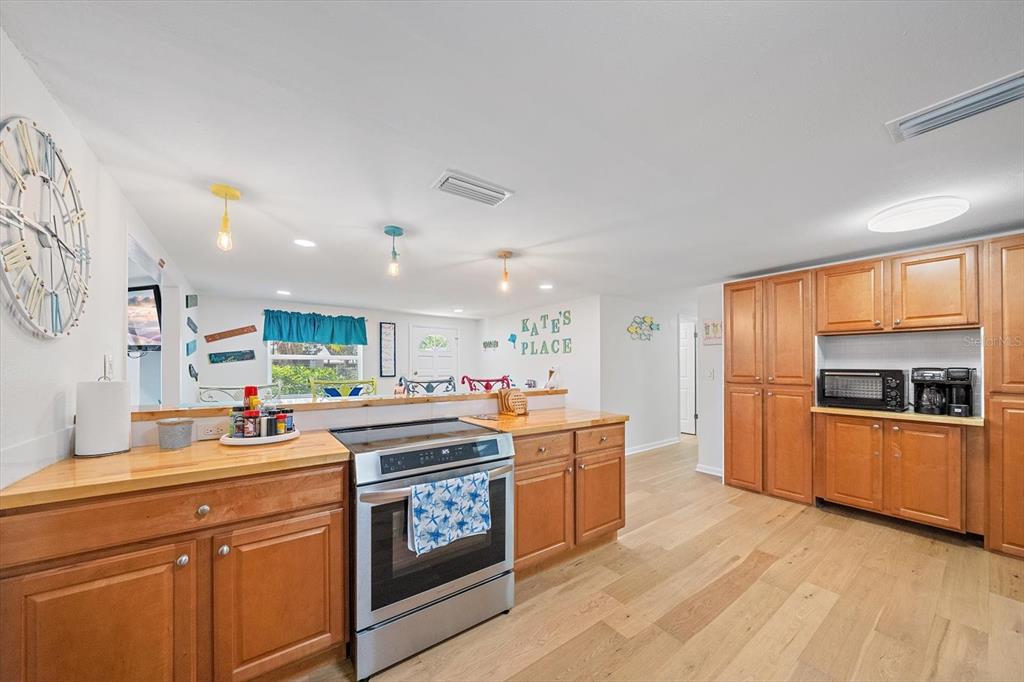 A kitchen features wooden cabinets, a stainless steel stove, and light-colored wood flooring — 2923 LINWOOD DRIVE, SARASOTA, FL