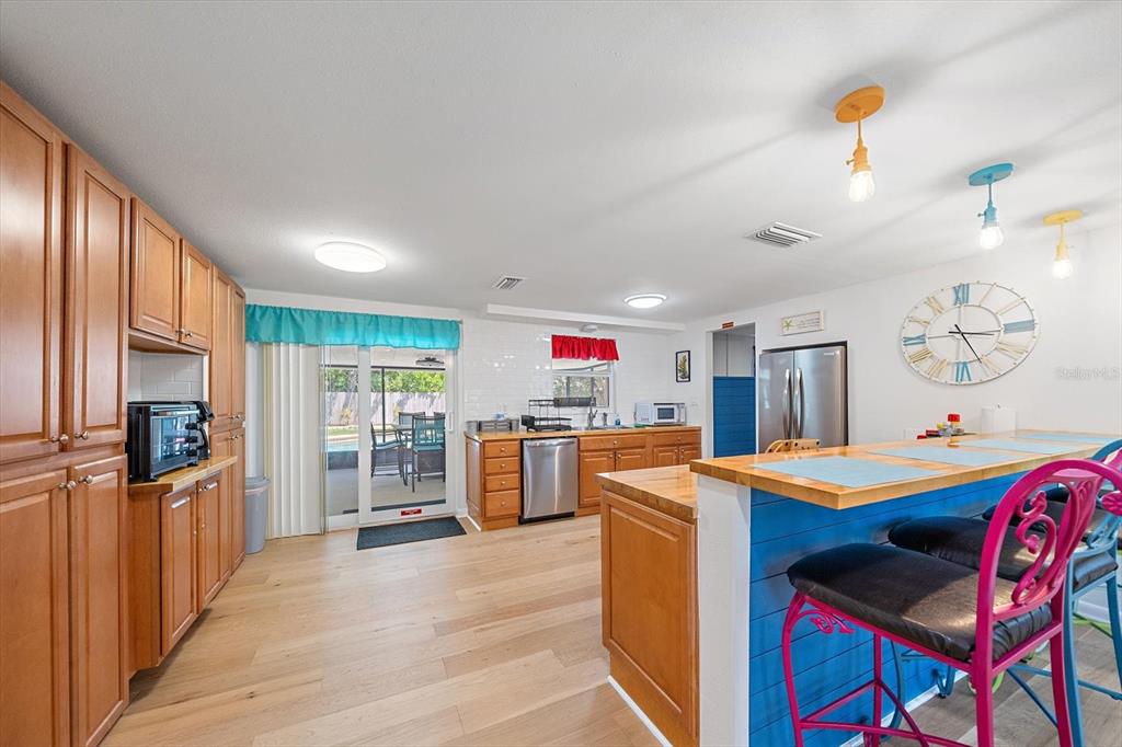 A kitchen features wood cabinets, a blue island with bar stools, and a sliding glass door — 2923 LINWOOD DRIVE, SARASOTA, FL