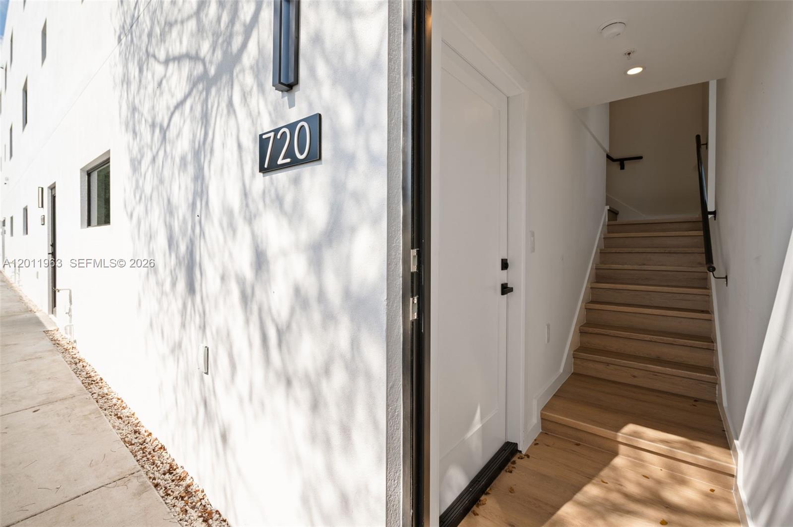 An exterior view shows a white building entrance with a staircase leading upward — 720 NW 55th Ter # 720, Miami FL 33127, MIAMI, FL