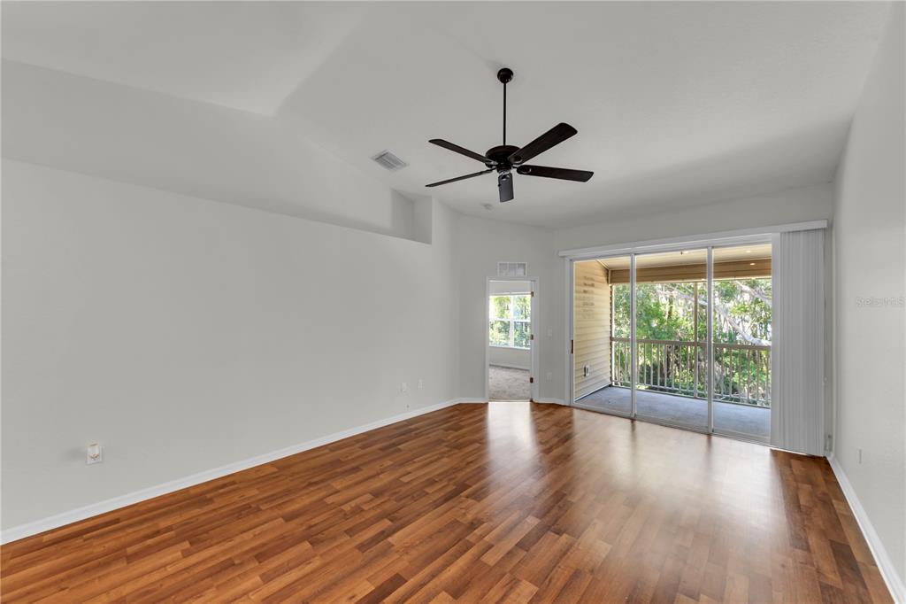 An empty room with wood-look flooring, a ceiling fan, and a sliding glass door balcony — 1715 HAMMOCKS AVENUE UNIT 1715, LUTZ, FL
