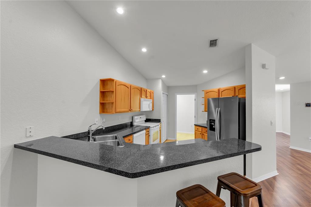 A kitchen with light wood cabinets, dark granite countertops, and a breakfast bar — 1715 HAMMOCKS AVENUE UNIT 1715, LUTZ, FL