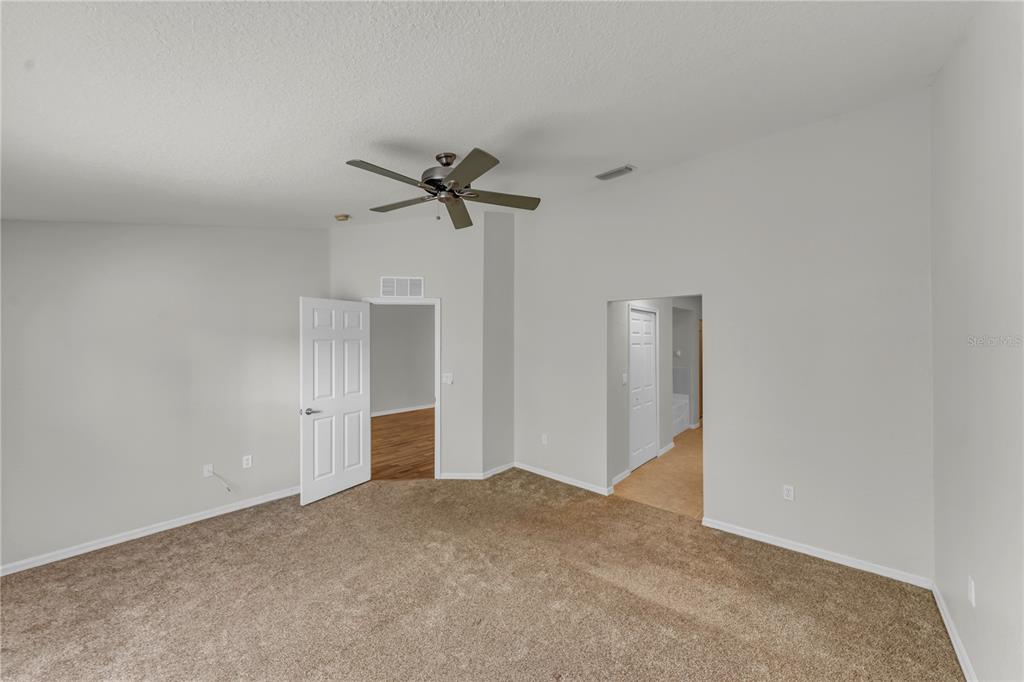 An empty bedroom features beige carpeting, light gray walls, a ceiling fan, and two doorways — 1715 HAMMOCKS AVENUE UNIT 1715, LUTZ, FL