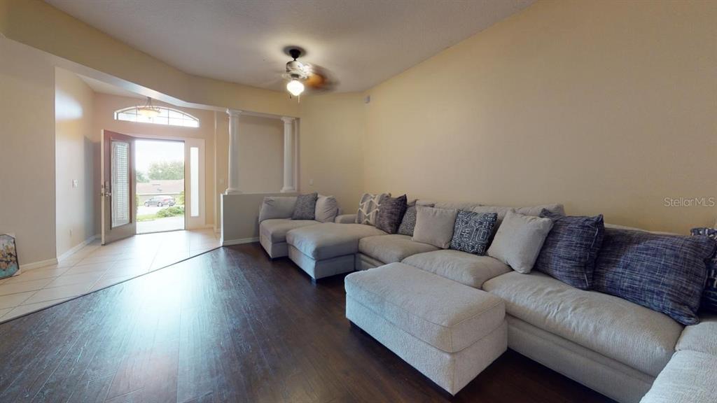 A living room features a large sectional sofa, dark wood flooring, and an open entryway — 3552 MACAULEY COURT, OCOEE, FL