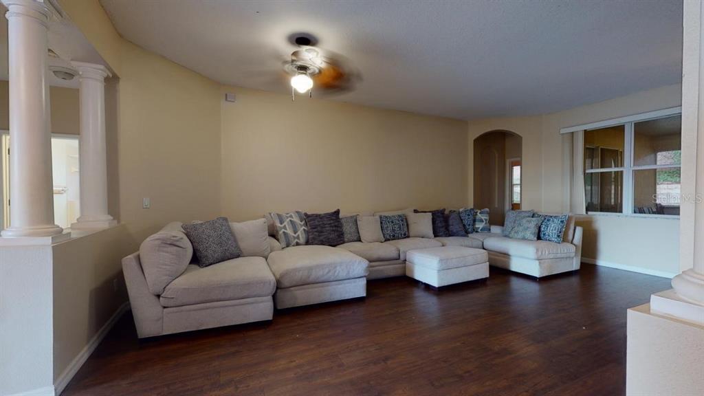 A living room features a large sectional sofa, dark wood flooring, and white columns — 3552 MACAULEY COURT, OCOEE, FL